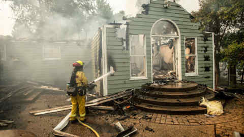 A CalFire firefighter douses flames on a burning home during the Carr fire in Redding, California on July 27, 2018. - &quot;Two firefighters have been killed in the Carr fire. A private contractor (operating) a bulldozer died yesterday and a Redding City firefighter was killed in the evening,&quot; a spokesman for Calfire, the state's Department of Forestry and Fire Protection, told AFP. (Photo by JOSH EDELSON / AFP) (Photo credit should read JOSH EDELSON/AFP/Getty Images)