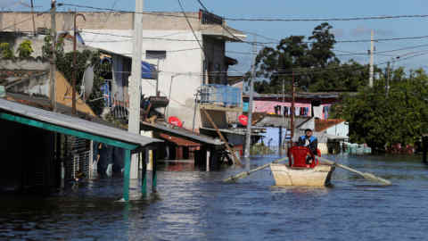 A man is seen in a boat in a flooded street after heavy rains caused Paraguay River to overflow, in a neighbourhood on the outskirts of Asuncion, Paraguay May 25, 2019. Picture taken May 25, 2019. REUTERS/Jorge Adorno