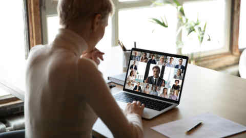 2BCW53M Woman sitting at desk watching new videoconference application online review