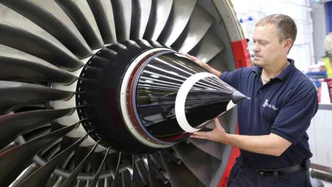 An employee fits the nose cone to a Trent 700 aircraft engine on the production line at the Rolls-Royce Holdings Plc factory in Derby, U.K., on Wednesday, Aug. 19, 2015. Rolls-Royce's XWB engine developed for the Airbus A350 should bring in twice the cash flow than the existing Trent 700 model on the Airbus A330, Chief Executive Warren East said in July. Photographer: Chris Ratcliffe/Bloomberg