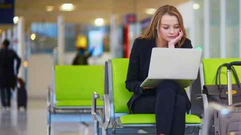 Passenger works on laptop at airport terminal