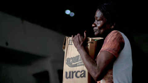 (FILES) In this file photo taken on April 07, 2020 a woman carries a box with donations of basic food supplies distributed by an NGO to people suffering during the novel coronavirus (COVID-19) outbreak at the Cidade de Deus (City of God) favela in Rio de Janeiro, Brazil. - Poor access to care, very exposed jobs, precarious housing: African descendants in Brazil are being hit hard by the new coronavirus, which throws light on racial inequalities in the country, since they represent the majority of the population. (Photo by MAURO PIMENTEL / AFP) (Photo by MAURO PIMENTEL/AFP via Getty Images)