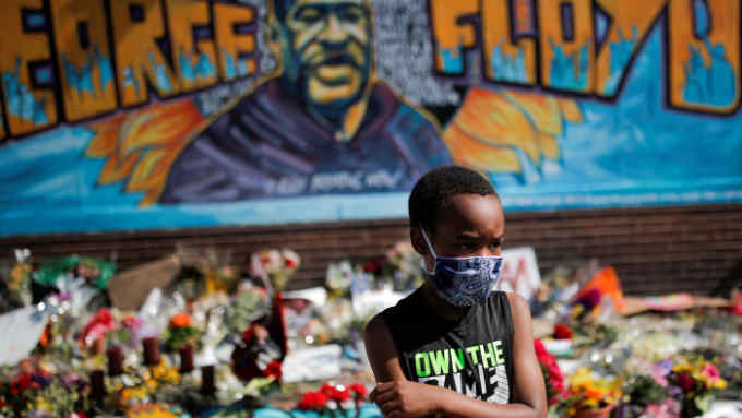 A child wears a protective mask at a makeshift memorial honoring George Floyd, at the spot where he was taken into custody, in Minneapolis, Minnesota, U.S., June 1, 2020. REUTERS/Carlos Barria