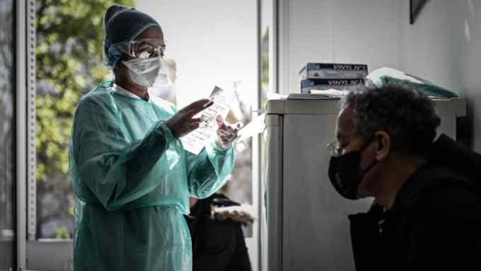 A staff member of a medical center testing patient for the COVID-19 virus checks a document in Paris on March 27, 2020 during a strict lockdown in France aimed at curbing the spread of the COVID-19 infection, caused by the novel coronavirus. (Photo by Philippe LOPEZ / AFP) (Photo by PHILIPPE LOPEZ/AFP via Getty Images)