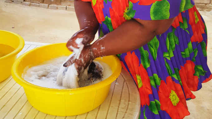 a South African woman washes clothes using water-saving soap powder