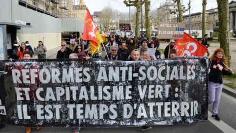 Protesters hold a banner reading &quot;anti-social reforms and green capitalism: it's time to land&quot; during a demonstration for climate change in Bordeaux, despite the authorities' recommendations to limit gatherings amid the outbreak of COVID-19, caused by the novel coronavirus, on March 14, 2020. (Photo by MEHDI FEDOUACH / AFP) (Photo by MEHDI FEDOUACH/AFP via Getty Images)