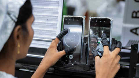 An employee tests the camera quality of mobile phones on an assembly line in the mobile phone plant of Rising Stars Mobile India Pvt., a unit of Foxconn Technology Co., in Sri City, Andhra pradesh, India, on Thursday, July 11, 2019. Foxconn, also known as Hon Hai Precision Industry Co., opened its first India factory four years ago, it now operates two assembly plants with plans to expand those and open two more. The company was integral to China’s transformation into a manufacturing colossus, and founder Terry Gou has told India's Prime Minister Narendra Modi that Foxconn could help India do the same. Photographer: Karen Dias/Bloomberg