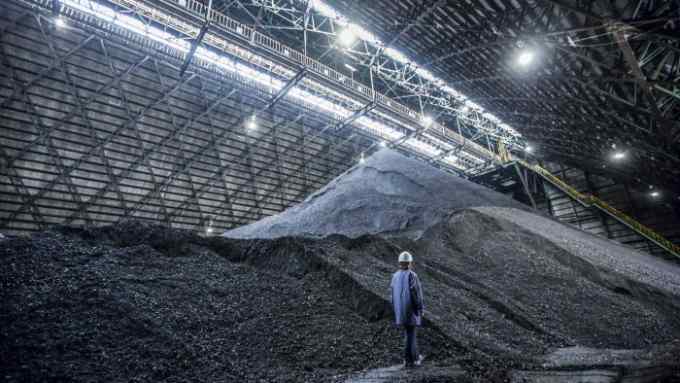 An employee walks in a coal storage yard at the Joban Joint Power Co. Nakoso coal-fired power station in Iwaki City, Fukushima Prefecture, Japan, on Wednesday, Aug. 1, 2012. With the loss of nuclear plants, which produced more than 25 percent of Japan’s electricity before the disaster, the country have had to rely on oil, coal and gas-fired plants. The cost of importing those fuels has driven the country into a trade deficit for 18 straight months while the current-account shortfall widened to a record in November. Photographer: Tomohiro Ohsumi/Bloomberg