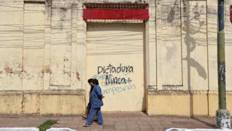 Two women walk past a graffiti that reads &quot;Dictatorship, never again&quot; as they leave after the inauguration ceremony of Mario Abdo Benitez as the country's new president in Asuncion, Paraguay August 15, 2018. REUTERS/Marcos Brindicci - RC1B11402E20