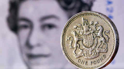 A one pound sterling coin sits in front of a British five pound banknote in this arranged photograph in London, U.K., on Tuesday, Feb. 9, 2016. The pound has been falling versus the dollar since the middle of 2015 and accelerated its slide this year, reaching an almost seven-year low of $1.4080 on Jan. 21. Photographer: Chris Ratcliffe/Bloomberg