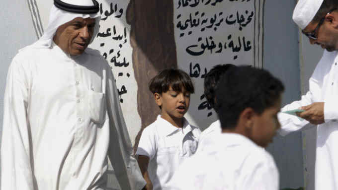 Parents wait to pick up their children as boys head out of the gates of a primary school in the western village of Karzakan, Bahrain, on Sunday, Oct. 30, 2011. As of Oct. 31, according to the U.N. Population Fund, there will be 7 billion people sharing Earth's land and resources. (AP Photo/Hasan Jamali)