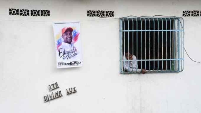 A man watches from a window the opposition leader of Voluntad Popular party, Edmundo Rada funeral at the Petare neighborhood, Caracas, on October 20, 2019. - Rada, was found dead outside the neighborhood of Petare under circumstances not yet clarified last October 17, 2019. (Photo by Yuri CORTEZ / AFP) (Photo by YURI CORTEZ/AFP via Getty Images)