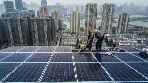 WUHAN, CHINA - MAY 15: Chinese workers from Wuhan Guangsheng Photovoltaic Company work on a solar panel project on the roof of a 47 story building in a new development on May 15, 2017 in Wuhan, China. China consumes more electricity than any other nation, but it is also the world's biggest producer of solar energy. Capacity in China hit 77 gigawatts in 2016 which helped a 50% jump in solar power growth worldwide. China is now home to two-thirds of the world's solar production, though capacity and consumption remain low relative to its population.  Still, the country now buys half of the world's new solar panels Ñ which convert sunlight into energy,  and are being installed on rooftops in cities and across sprawling fields in rural areas.  Greenpeace estimates that by 2030, renewable energy could replace fossil fuels as China's primary source of power, a significant change in a country considered the world's biggest polluter.  China's government has officially committed to development of renewable energies to ease the countryÕs dependence on coal and other fossil fuels, though its strategic investments in the solar panel have created intense global competition. (Photo by Kevin Frayer/Getty Images)