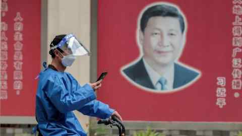 A cyclist rides past a poster of Xi Jinping in Shanghai