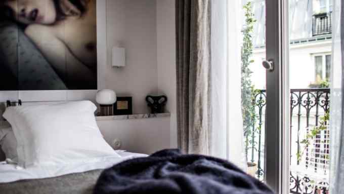 A bedroom in Le Pigalle hotel, with grey walls and artwork featuring a topless woman behind the bed