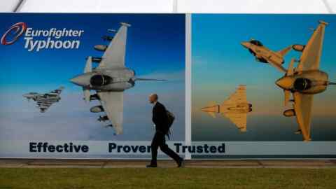A man walks past a poster advertising the Eurofighter Typhoon fighter jet