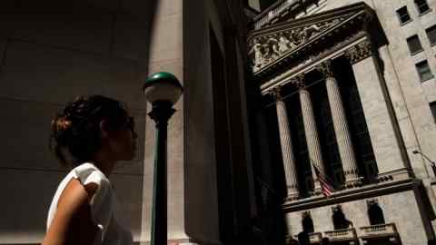A woman walks past the New York Stock Exchange