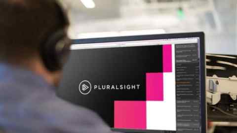 A worker looks at a computer screen with the Pluralsight logo on it