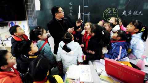 A teacher shows a lunar probe model to primary school children in Yunyang county in southwestern China’s Chongqing last December