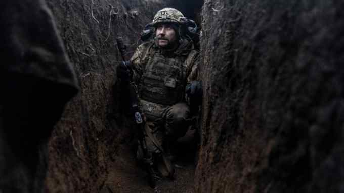 A Ukrainian soldier crouches in a trench