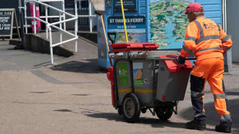 A street cleaner with his cart and bins on the waterfront area in Falmouth, Cornwall