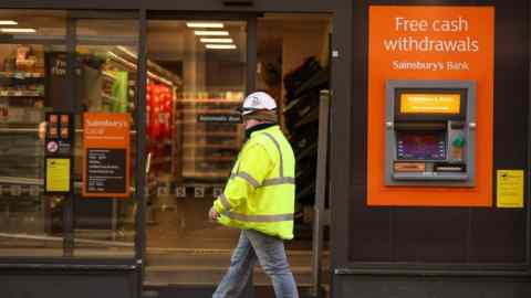 A person walks past a Sainsbury’s Bank cash machine