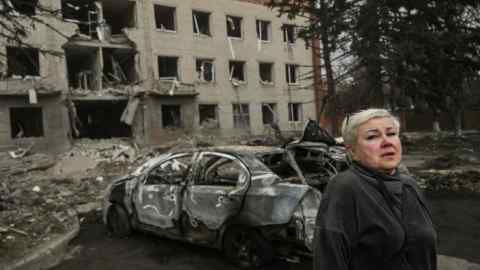 A woman stands in front of a destroyed building after a deadly strike in the eastern Ukraine town of Sloviansk