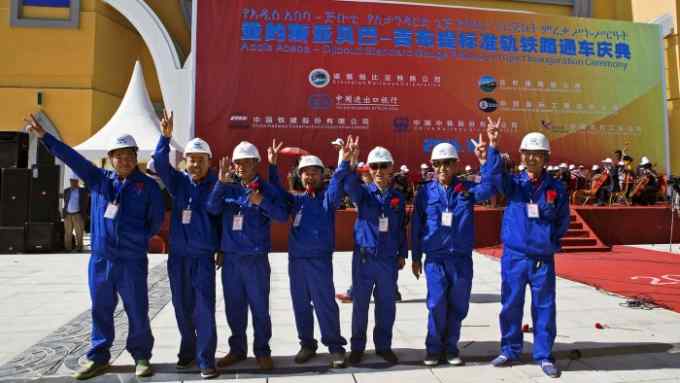 All aboard: Chinese workers cheer the opening of the Addis-Djibouti line but it is used less than envisaged