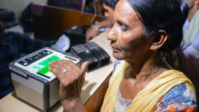 An Indian woman getting her fingerprints read during the registration process for Aadhaar cards