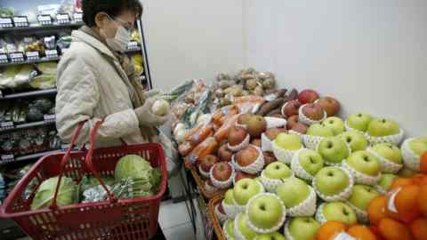 A woman shops for fruits and vegetables in a grocery