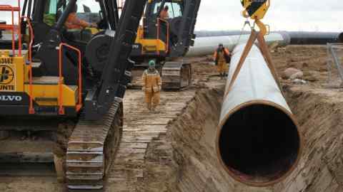 a huge pipeline being lowered into the ground using heavy equipment