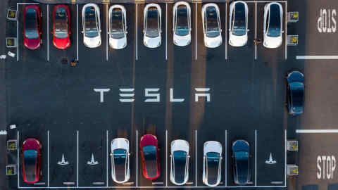 Two rows of Tesla cars seen from above face each other in a parking lot