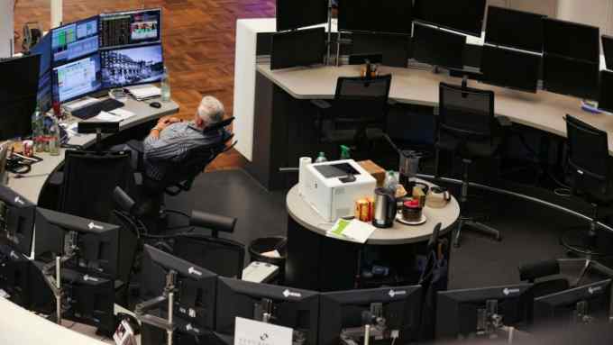 A solitary trader monitors financial data near empty desks on the trading floor at Frankfurt Stock Exchange in Germany