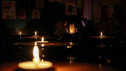 People sit in a candlelit pub in Lviv, Ukraine during a power outage caused by Russian missile attacks