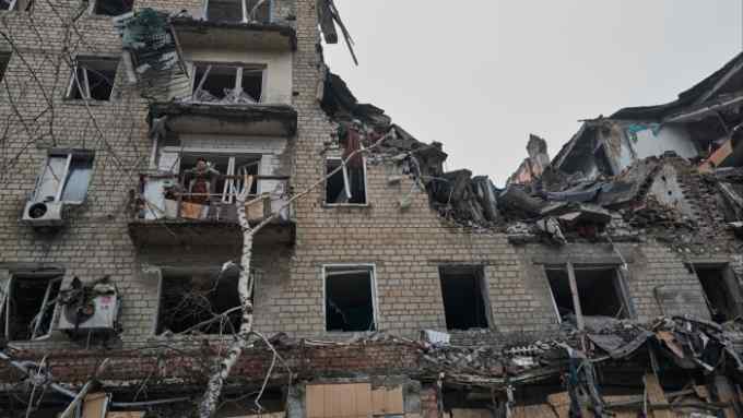 An elderly woman stands on the balcony of her destroyed house in the city of Avdiivka