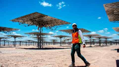 A worker walks near solar panels at Cerro Dominador, in Latin America