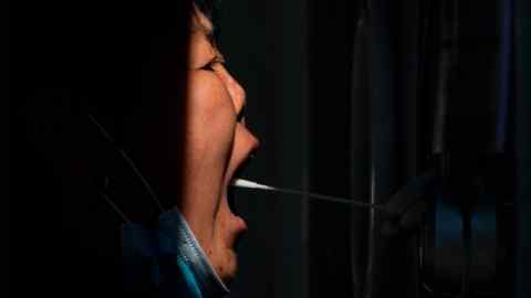 A woman gets a Covid-19 throat swab at a coronavirus testing site in Beijing