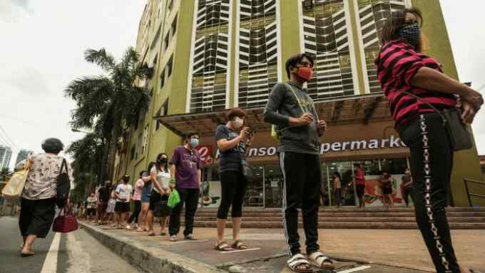 Shoppers in Manila maintain social distance while queuing