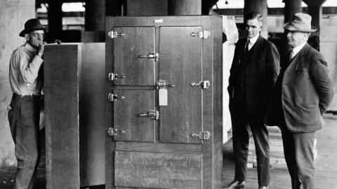 Men stand beside the first frigidaire, a device developed as a means to store perishable foods which todays plays a vital role in medical research and has enabled a global vaccine rollout