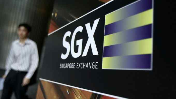 An office worker walks past the logo of SGX in the financial district of Singapore