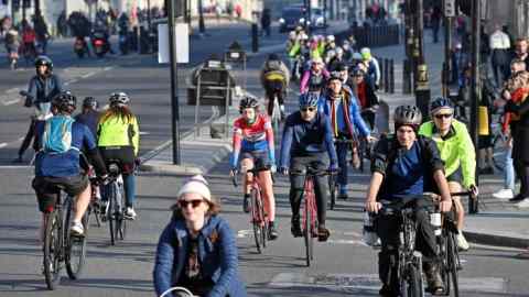 People ride bicycles in the cycle lane as they cross Westminster Bridge into Parliament Square in London on November 7, 2020