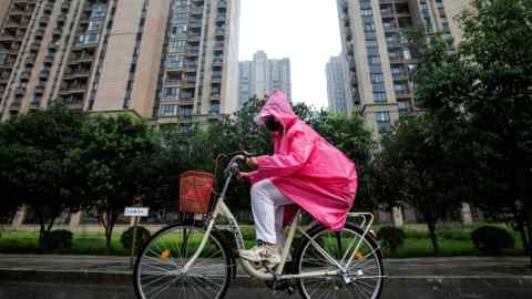 A resident cycles in the rain through the Evergrande residential buildings in Wuhan