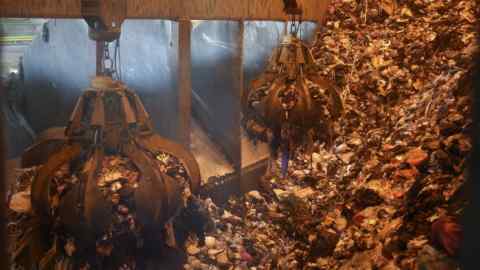 Two large grabbers transport the waste from a large pile