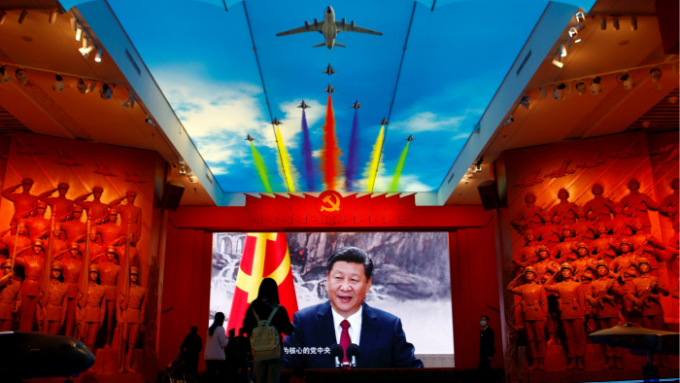 Visitors stand in front of a giant screen displaying China’s president Xi Jinping next to a flag of the Communist party of China at a military musuem in Beijing