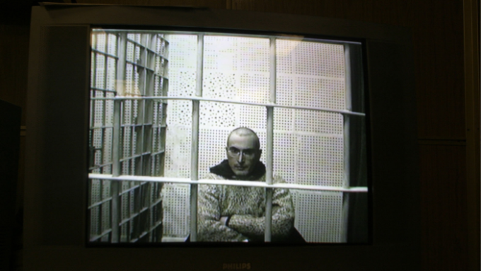A black-and-white CCTV image of Mikhail Khodorkovsky in a cell