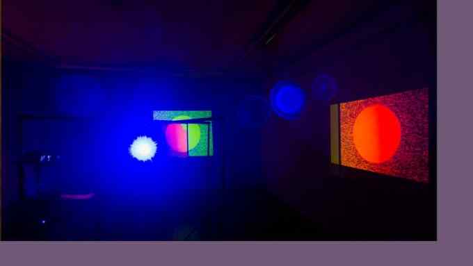 Bright spots of coloured light are projected on to a dark wall