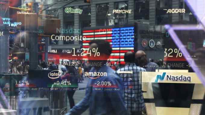 People are reflected in the window of the Nasdaq MarketSite in Times Square in New York