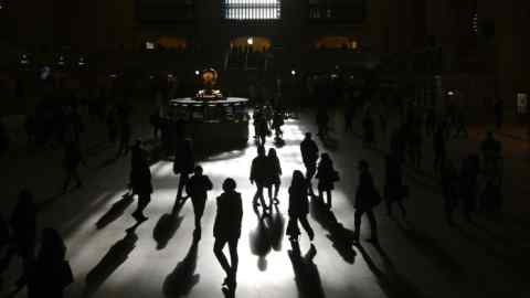 Commuters walk through the morning bright sunlight coming from windows in Grand Central Terminal in New York City