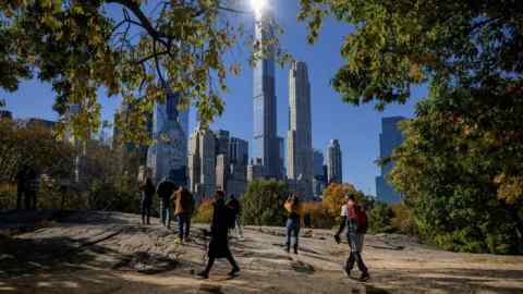 Passers-by in Central Park, New York, with high-rise buildings in the background