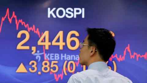 A man looks at a screen featuring the Kospi index